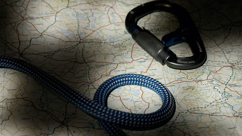 A climbing rope and carabiner resting on a folded topographic map.