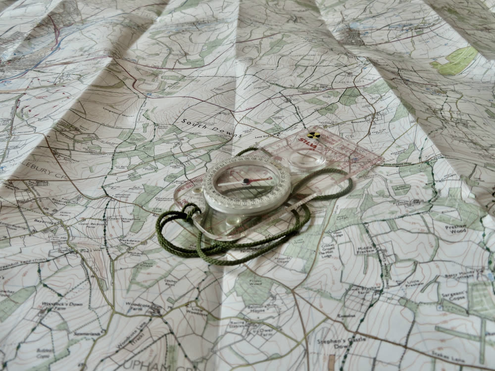 A compass resting on a topographic map.