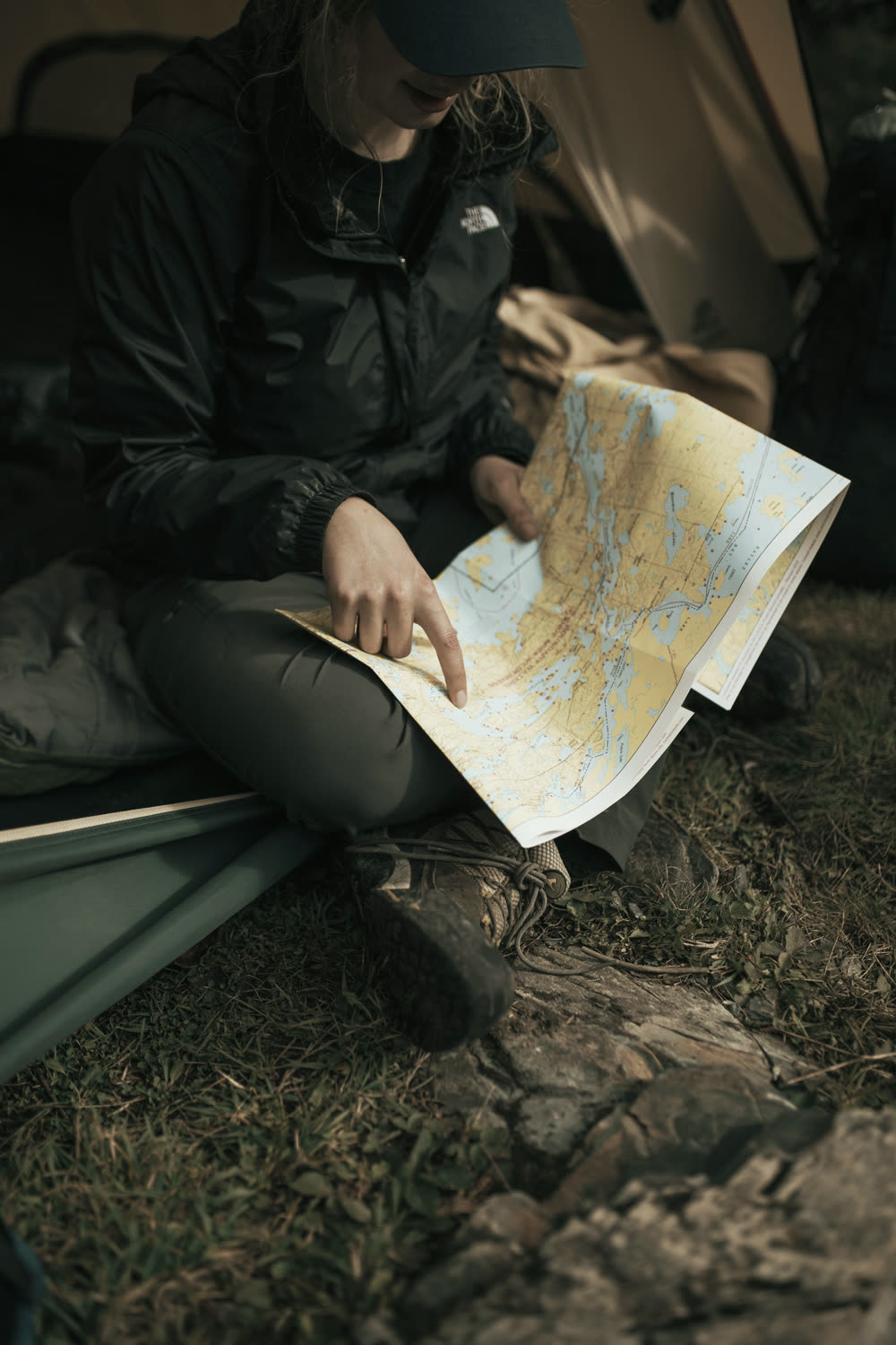 A person sitting outside a tent reading a paper map.