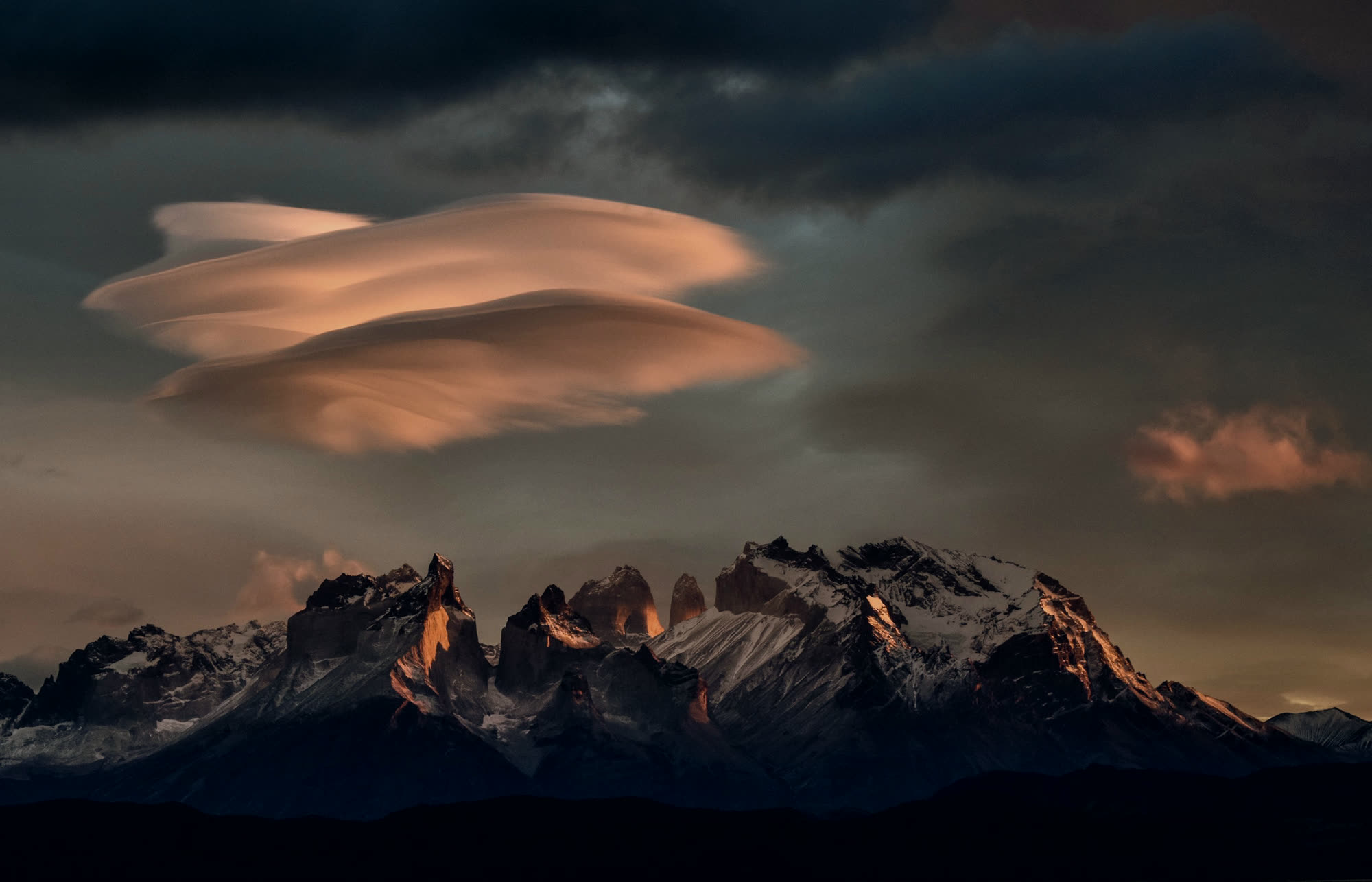 A lenticular cloud burning orange above the Paine massif at sunset.